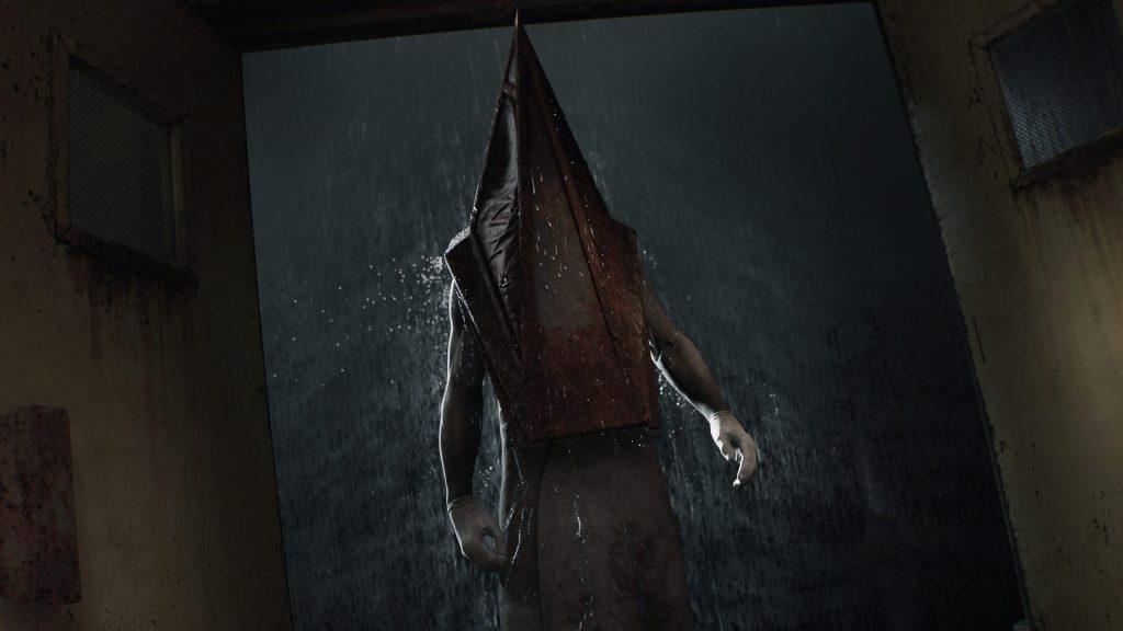 Silent Hill 2 Remake ekran görüntüsü, piramit kafa karanlık bir ortamda yağmurun altında bir kapı eşiğinde bekliyor.